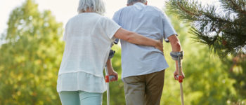 Senior mit Krückstock beim Gehen in der Reha im Garten